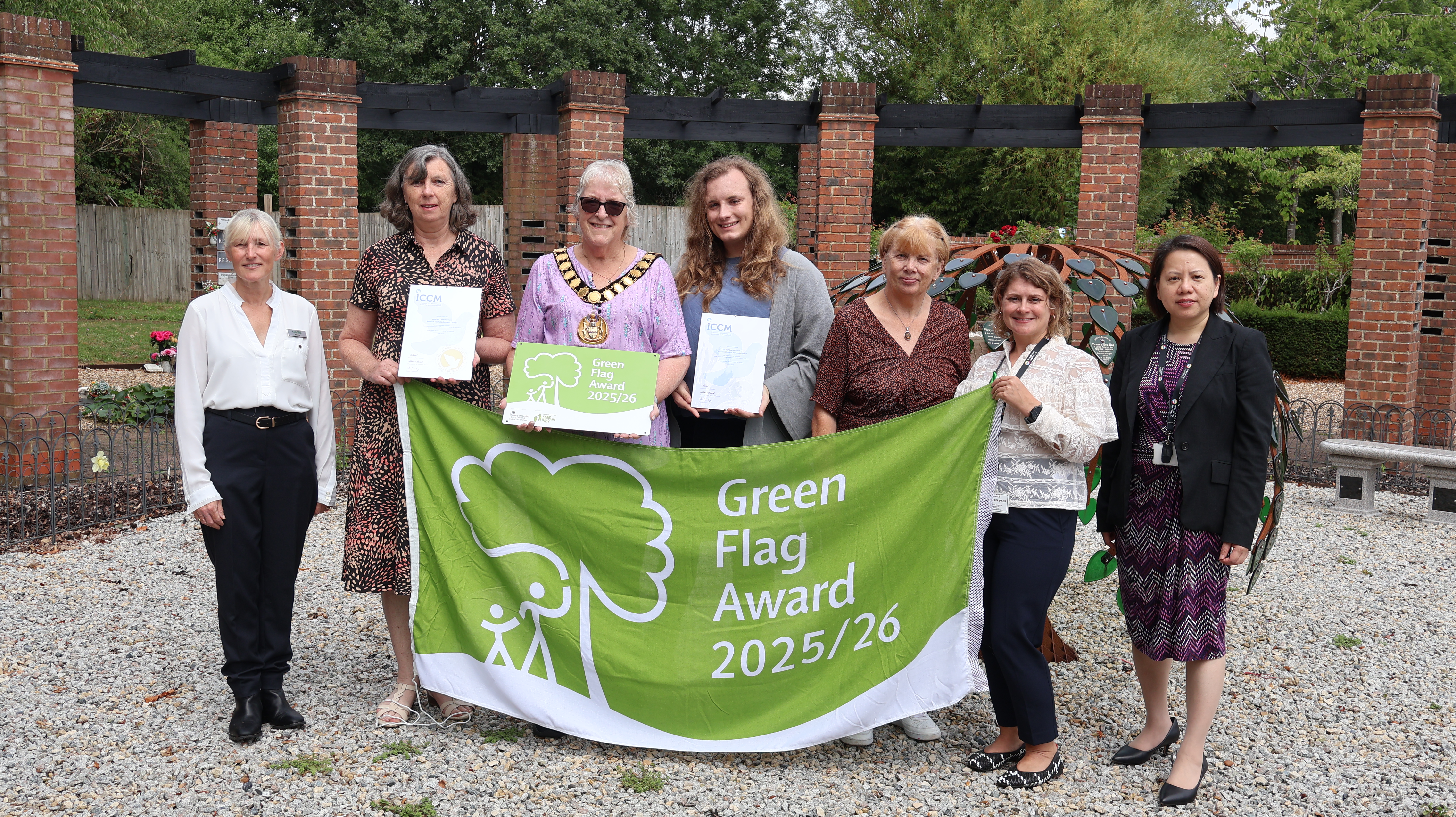 Staff standing together holding the green flag award banner